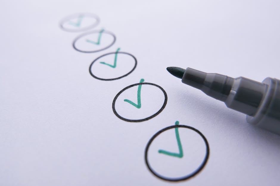 Close-up image of a white sheet of paper with six circles drawn in black ink, each containing a green checkmark. A black marker pen with a gray cap is positioned on the right side, with its tip pointi